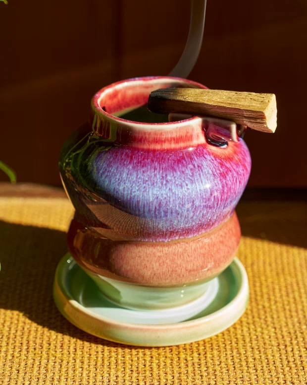 A purple and pink glazed ashtray stacked on its saucer in warm light