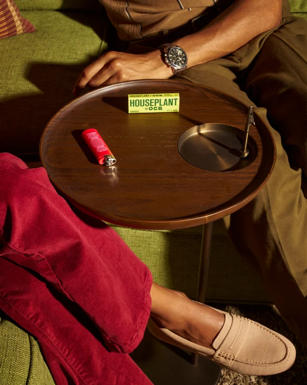 Seen from above: a round brown side table with a built-in ashtray between two people on a sofa