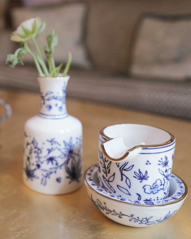 A blue-and-white floral ashtray and vase with a green sprig, on a wooden table